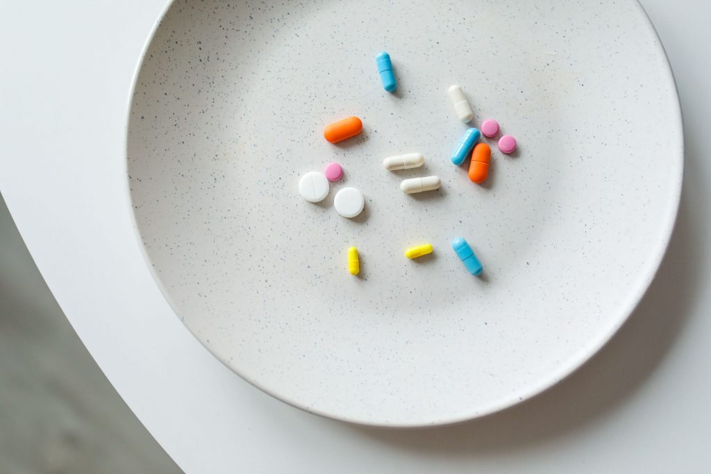 A variety of colorful medicine pills arranged on a white plate, symbolizing healthcare.